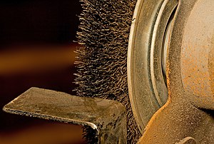 A circular wire brush mounted to an 205mm (8in) bench grinder with a tool rest in front.