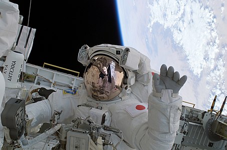 During mission's second spacewalk STS-114 astronaut Soichi Noguchi waves from the Shuttle payload bay.